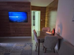 a dining room with a table and a television on a wall at צימר ליאלינא in Ein Kinya