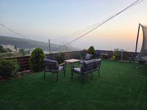 a table and chairs on a lawn with a view at צימר ליאלינא in Ein Kinya
