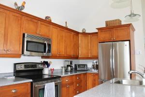 a kitchen with wooden cabinets and a stainless steel refrigerator at Couples Cove Cottage in Ellsworth