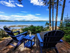 two chairs and a table with a view of a lake at Couples Cove Cottage in Ellsworth