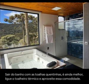 a bathroom with a tub and a large window at Refúgio da Realeza in Urubici