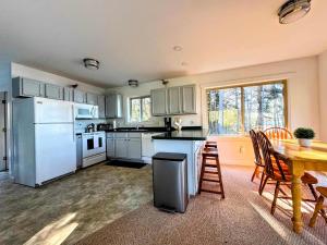 una cucina con elettrodomestici bianchi e un tavolo con sedie di Sunset Cove Cottage private beach a Prospect Harbor