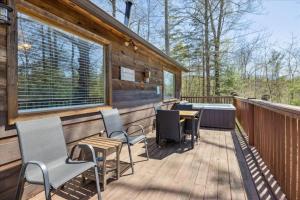 a deck with chairs and a table and a tub at A Dream Romance Cabin With Hot Tub & Fireplace in Sevierville