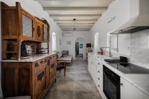 a large kitchen with white cabinets and a living room at Cycladic Wine Press House in Aliki
