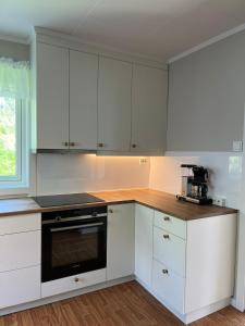 a kitchen with white cabinets and a black oven at Flo Lake House in Stryn
