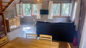 een woonkamer met een tafel, stoelen en ramen bij La Rubina in Villa Ventana