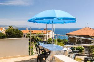 una mesa azul y sillas en un balcón con sombrilla en Jana's Flat - Seafront apartment, en Fertilia