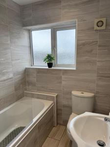 a bathroom with a tub and a toilet and a sink at Valletta House Holiday Apartments in Skegness