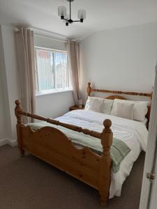a bedroom with a wooden bed and a window at Valletta House Holiday Apartments in Skegness