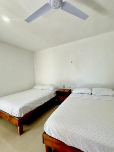 two beds in a room with a ceiling fan at Casa GLEZAR el cuyo in El Cuyo