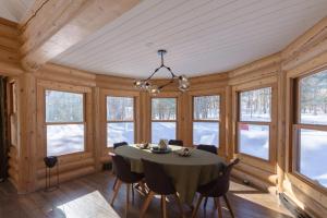 a dining room with a table and chairs and windows at Relaxing Sauna and Hot Tub, Near Ski Slopes,Trails in Mille-Isles