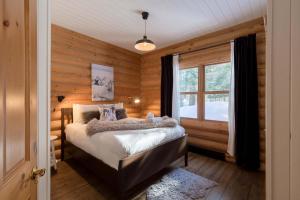 a bedroom with a bed in a room with wooden walls at Relaxing Sauna and Hot Tub, Near Ski Slopes,Trails in Mille-Isles