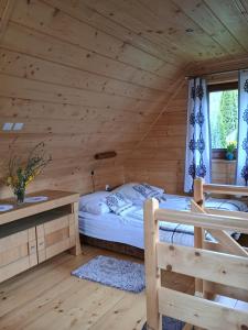 a bedroom in a log cabin with a bed and a desk at Chatka pod Lubaniem in Ochotnica Dolna