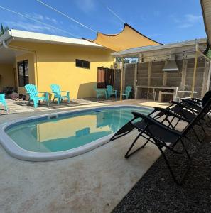 a swimming pool with chairs and a table and a house at Bandera Beach Cabins in Parrita