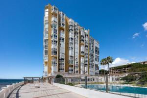 a large building with a swimming pool next to the ocean at Fancy Studio Direct Access to Sea✺Parking✺Pool in Mijas +42 photos