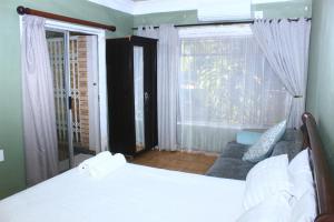 une chambre avec un lit, une fenêtre et un canapé dans l'établissement Ankuweni Guest house, à Giyani