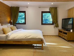 a bedroom with a bed and a flat screen tv at Mountain Chalet - Cabana la Muntele Baisorii in Muntele Cacovei