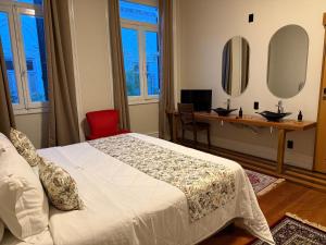 a bedroom with a bed and a desk and a mirror at Chalés e Pousada - Casarão Histórico by Pousada Princesa Isabel in Petrópolis