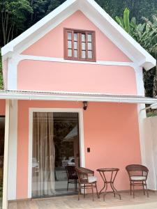 a pink building with chairs and a table in it at Chalés e Pousada - Casarão Histórico by Pousada Princesa Isabel in Petrópolis
