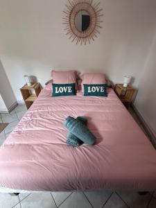a bedroom with a pink bed with love pillows at Le Cocon Fleuri in Auxerre