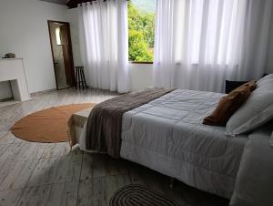 a bedroom with a bed and a window with white curtains at Chalé do Mato in Itatiaia +16 photos