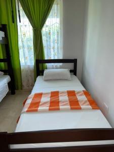 a bed with an orange and white comforter in a room at Cabaña Yopal - Yopo Resort in Yopal