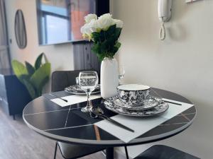 a table with plates and a vase with flowers on it at ASHRI Deluxe Studio in DSO, Near Silicon Mall in Dubai +30 photos
