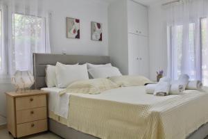 a white bedroom with a large bed with white pillows at Bright and Peaceful Apartment near Varkiza beach in Varkiza +34 photos