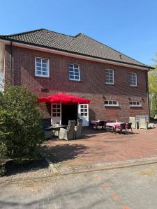HarkebrüggeにあるGasthaus Blockのテーブルと椅子と赤い傘のあるレンガ造りの建物