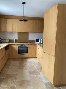 a kitchen with wooden cabinets and a stove top oven at Gite le Roucayral , vue imprenable sur St Cirq Lapopie, deux chambres climatisées in Tour-de-Faure