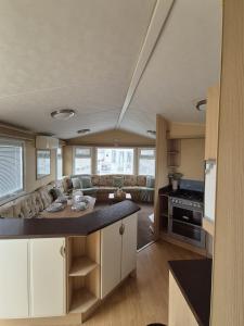 eine Küche und ein Wohnzimmer mit einer Couch und einem Tisch in der Unterkunft Meadow Lakes 64, pet friendly , WiFi & bed linen - Golden Palm Resort - Meadow Lakes Caravan & Lodge Hire in Chapel Saint Leonards