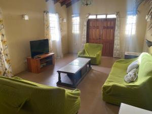 a living room with two green couches and a tv at GNC Guesthouse in Saint Peter