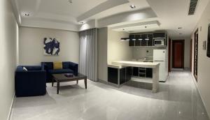a living room with a blue couch and a kitchen at ديباج للشقق المخدومة in Dammam