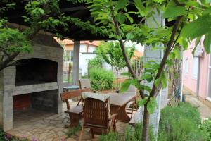 a patio with a table and a stone fireplace at Apartments Petani in Zadar