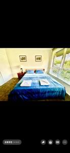 a bedroom with a blue bed with a window at Jalynn 1 Cottage in Glen Waverley