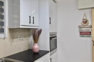 a kitchen with white cabinets and a vase on a counter at Bright and Peaceful Apartment near Varkiza beach in Varkiza