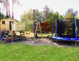 a playground with a slide and a swing set at Domek Letniskowy nad jeziorem Głuszyńskim in Orle
