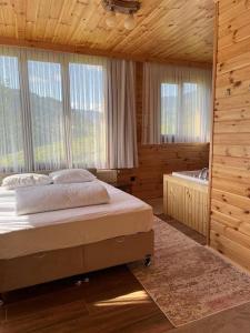 a bedroom with a bed and a tub and windows at Ayder Defne Suit Ev in Çamlıhemşin