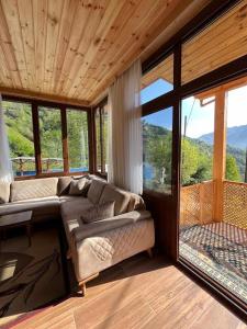 a living room with a couch in a room with windows at Ayder Defne Suit Ev in Çamlıhemşin