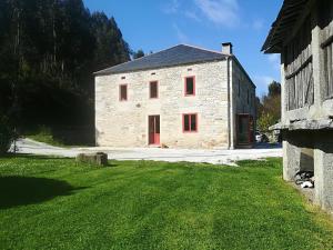 a large stone building with red windows in a yard at Confort, espacio y naturaleza in Jove