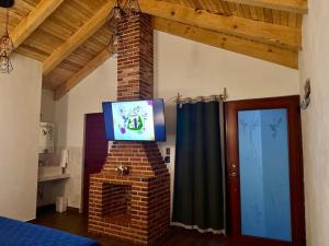 a living room with a tv on top of a brick fireplace at Cabaña para pareja con Jacuzzi in Huasca de Ocampo