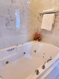 La salle de bains est pourvue d'une baignoire blanche et de murs en marbre. dans l'établissement Cabaña para pareja con Jacuzzi, à Huasca de Ocampo