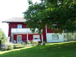 une maison rouge avec une pelouse devant dans l'établissement Ferienwohnung im Seidlerhof mit Terrasse, à Röhrnbach