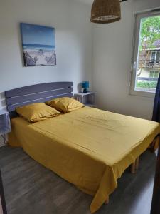 a bedroom with a large bed with a yellow bedspread at Terrasses du lac appt in Aureilhan
