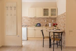 a kitchen with white cabinets and a table and chairs at Apartmani MARJANOVIĆ Pačir in Pačir