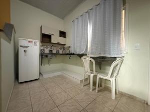 a kitchen with a refrigerator and two white chairs at Pousada Tortuga in Anchieta