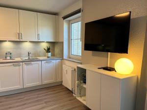 a kitchen with white cabinets and a flat screen tv at NEU 2025 - Fewo mit Meerblick & Flair in Harrislee