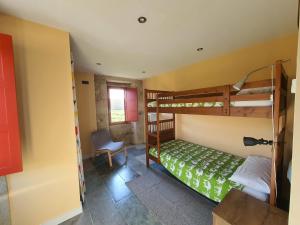 a bedroom with bunk beds and a desk and a chair at Confort, espacio y naturaleza in Jove