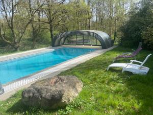 a swimming pool with two chairs next to a rock at L'Atelier du Canton proche Châteaux de la Loire et Beauval in Chissay-en-Touraine
