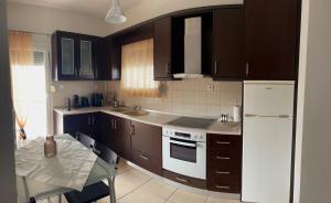 a kitchen with brown cabinets and a table and a white refrigerator at Vicky's house in Olympiada
